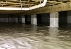 White vapor barrier covering a crawlspace floor between block piers
